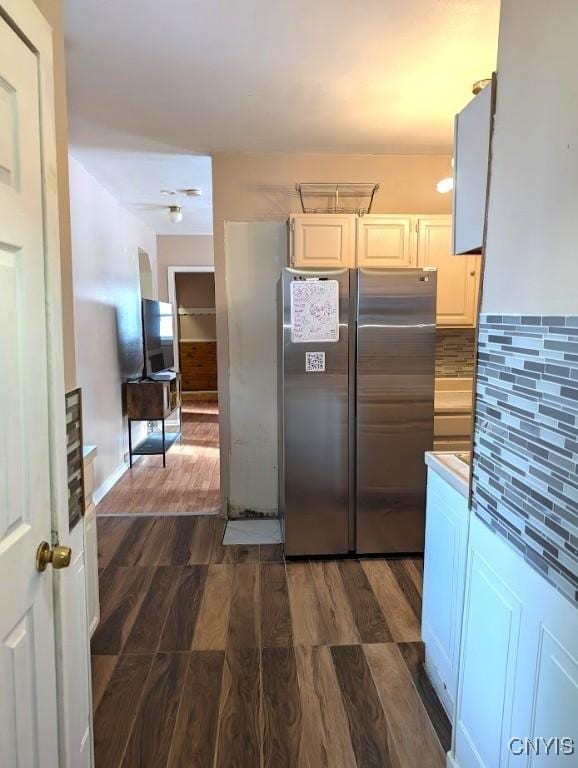 kitchen with dark hardwood / wood-style flooring, white cabinetry, stainless steel fridge, and tasteful backsplash