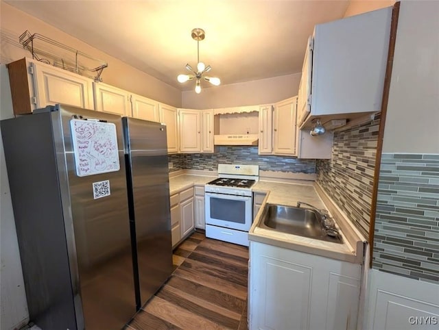 kitchen featuring pendant lighting, sink, stainless steel refrigerator, a notable chandelier, and white gas range