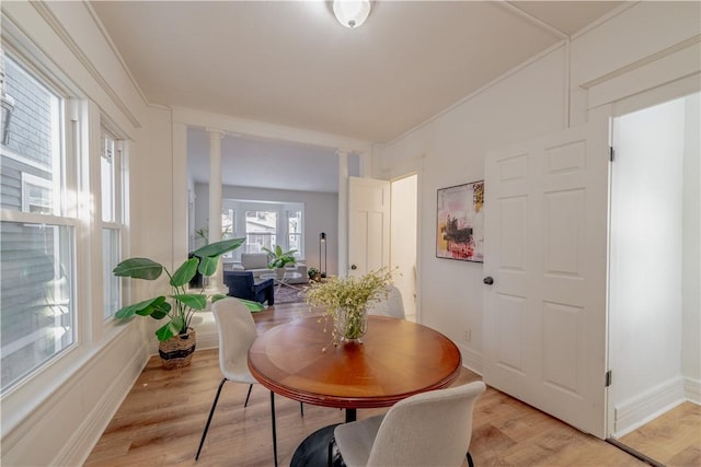 dining area with decorative columns, ornamental molding, and light hardwood / wood-style flooring