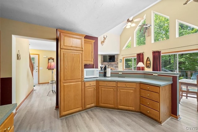 kitchen with ceiling fan, vaulted ceiling, and light hardwood / wood-style flooring