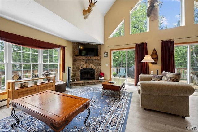 living room featuring a stone fireplace, a towering ceiling, and hardwood / wood-style floors