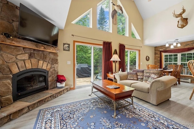 living room with a baseboard heating unit, a fireplace, light hardwood / wood-style floors, and high vaulted ceiling