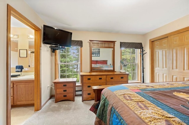 bedroom featuring a baseboard radiator, light colored carpet, ensuite bath, and a closet