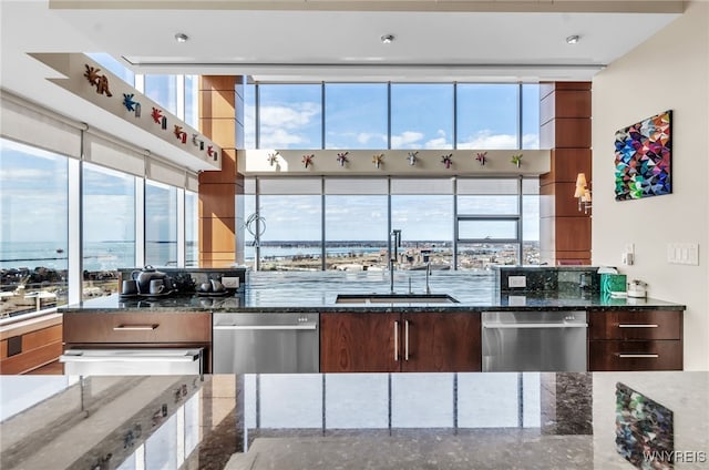 kitchen featuring dishwasher, a water view, sink, and dark stone counters