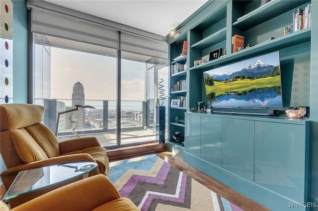 sitting room with expansive windows, a healthy amount of sunlight, hardwood / wood-style floors, and built in shelves