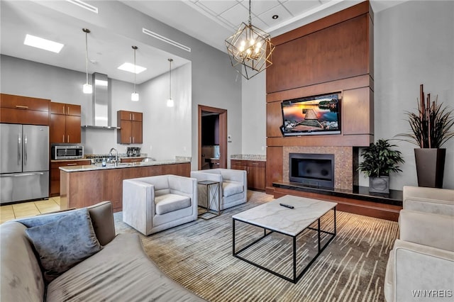 living room featuring a high ceiling, sink, a notable chandelier, and a skylight