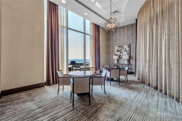 carpeted dining room featuring expansive windows, an inviting chandelier, and a high ceiling