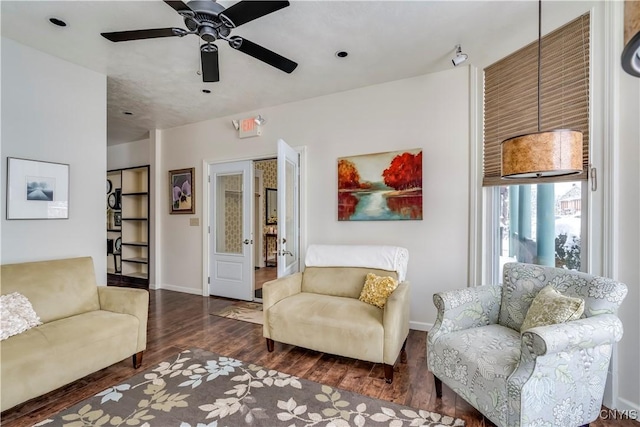 living room featuring ceiling fan and dark hardwood / wood-style floors