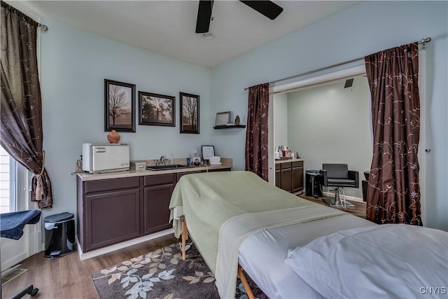 bedroom with sink, light hardwood / wood-style flooring, and ceiling fan