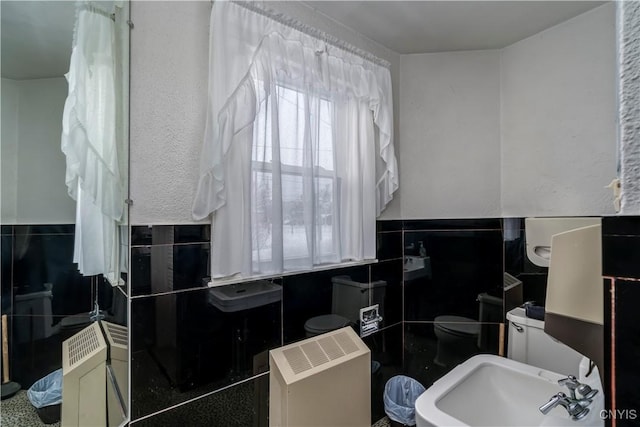 bathroom with sink, tile walls, and toilet