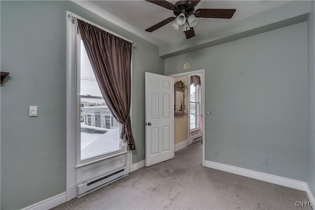 carpeted empty room with plenty of natural light, ceiling fan, and baseboard heating