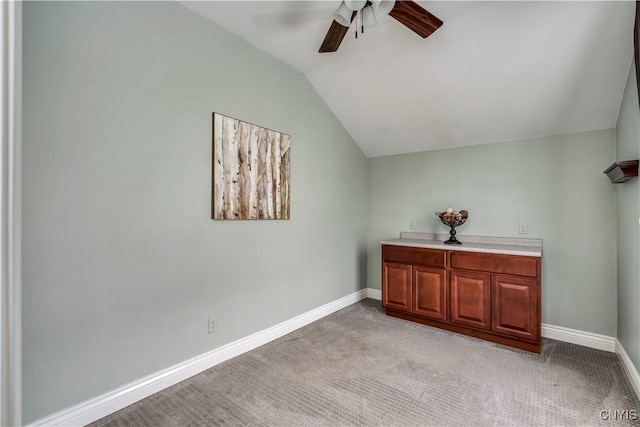 interior space with vaulted ceiling, light colored carpet, and ceiling fan