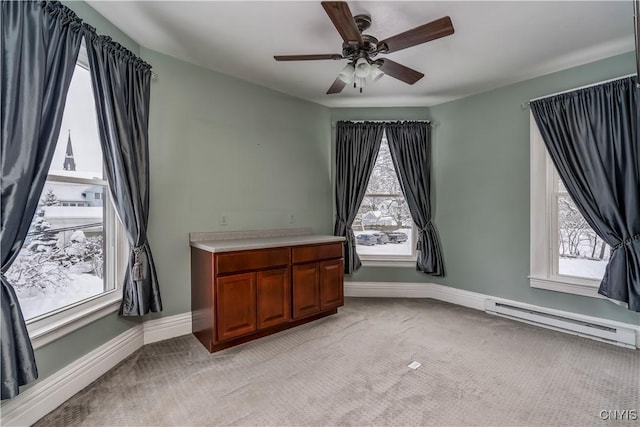 carpeted empty room featuring a healthy amount of sunlight, a baseboard heating unit, and ceiling fan