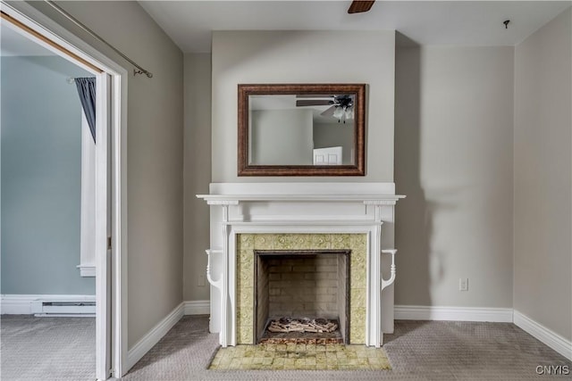 interior details featuring a tiled fireplace, carpet floors, and ceiling fan