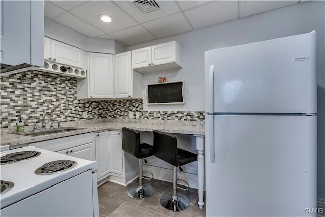 kitchen featuring sink, backsplash, white cabinets, a drop ceiling, and white appliances