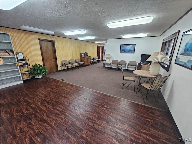 carpeted living room featuring wooden walls and a textured ceiling