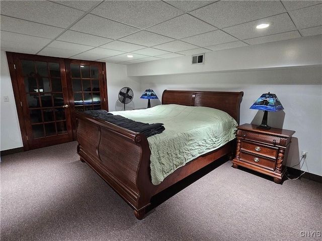 carpeted bedroom with a drop ceiling and french doors