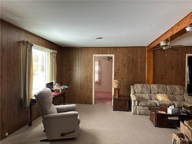 carpeted living room featuring ceiling fan and wood walls