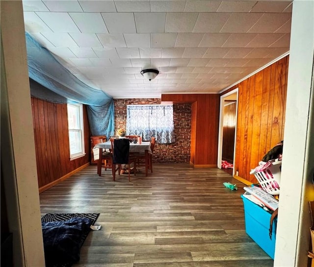 playroom with dark hardwood / wood-style flooring, wooden walls, and brick wall