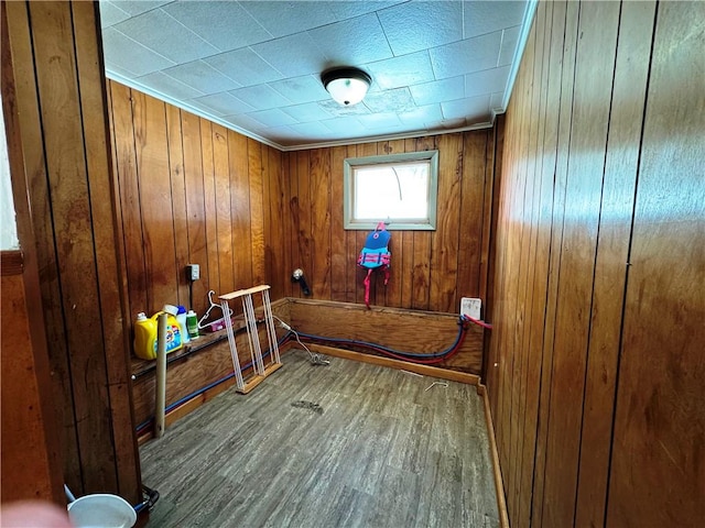 interior space with hardwood / wood-style flooring, ornamental molding, and wood walls