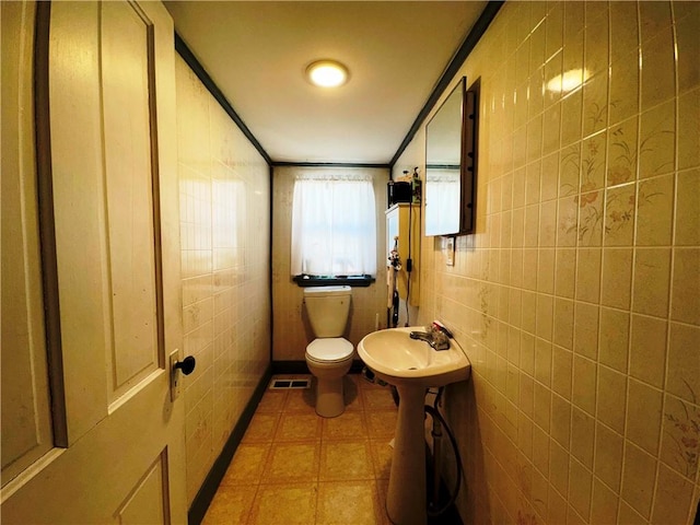 bathroom with tile walls, sink, and toilet