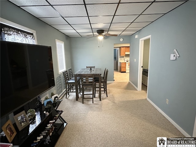 carpeted dining area with ceiling fan and a drop ceiling