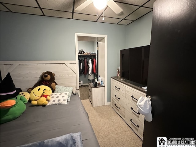 carpeted bedroom with ceiling fan, a drop ceiling, a closet, and a walk in closet