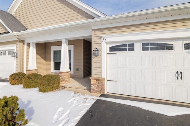 view of exterior entry with a garage and a porch