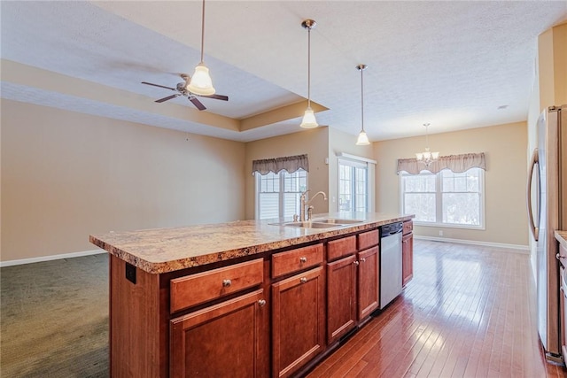 kitchen featuring stainless steel appliances, sink, decorative light fixtures, and an island with sink