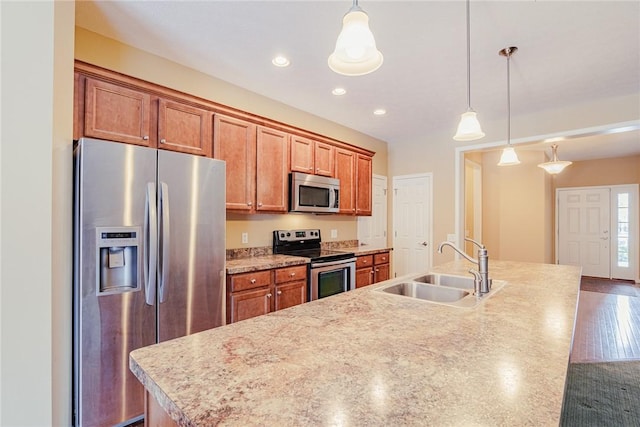 kitchen featuring sink, decorative light fixtures, an island with sink, and appliances with stainless steel finishes