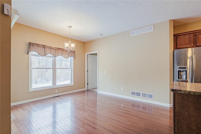 unfurnished dining area with light hardwood / wood-style flooring and a chandelier