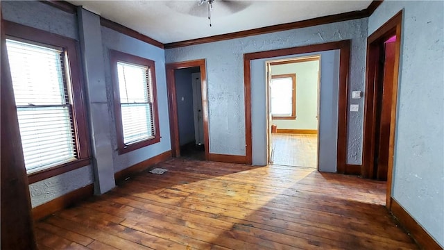 empty room with crown molding, ceiling fan, and dark hardwood / wood-style flooring