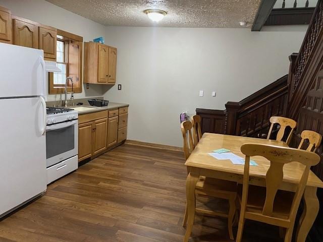 kitchen with sink, white appliances, dark wood-type flooring, and a textured ceiling