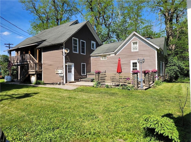 back of property featuring a wooden deck, a lawn, and a patio