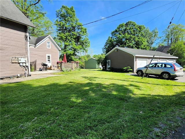 view of yard with a garage and an outbuilding