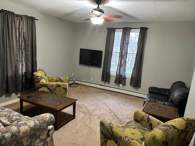 carpeted living room featuring a baseboard heating unit, a textured ceiling, and ceiling fan