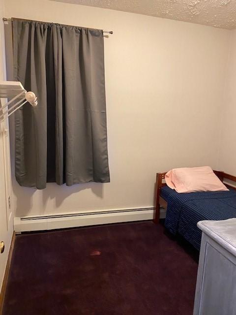 unfurnished bedroom featuring a baseboard radiator and a textured ceiling