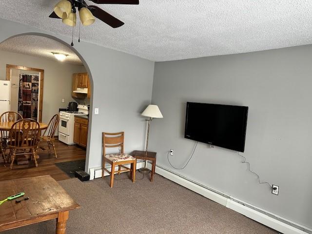 carpeted living room featuring ceiling fan, a baseboard heating unit, and a textured ceiling