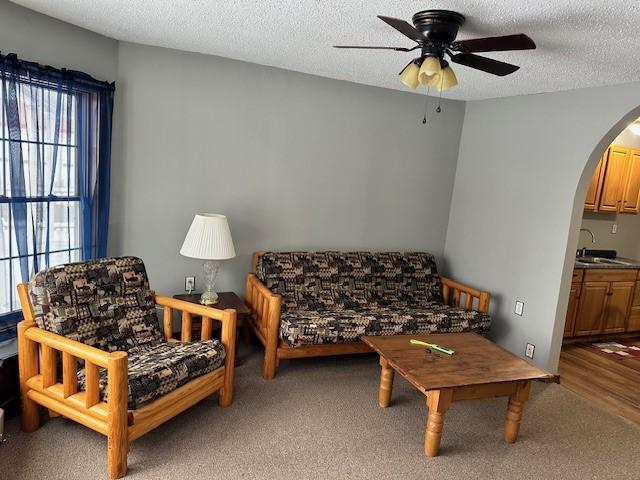 carpeted living room featuring sink, a textured ceiling, and ceiling fan