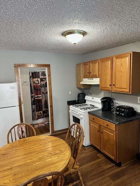 kitchen with dark hardwood / wood-style flooring, white appliances, and a textured ceiling