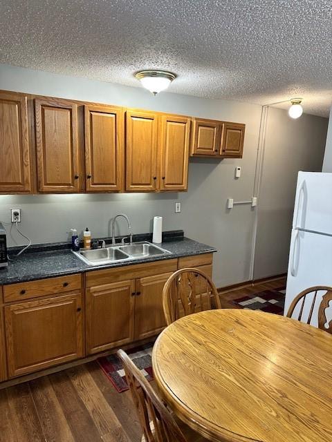 kitchen with dark hardwood / wood-style flooring, sink, white fridge, and a textured ceiling