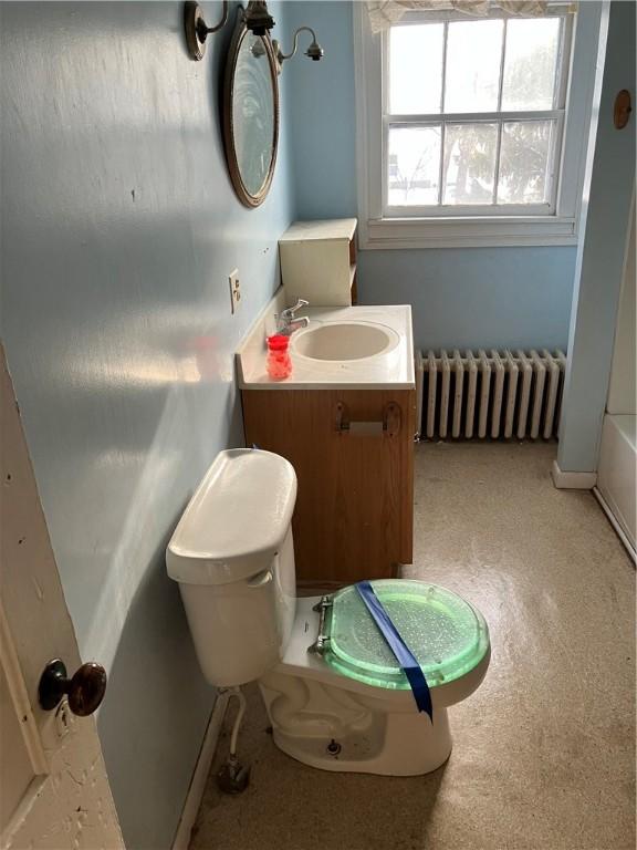 bathroom featuring vanity, radiator, a bath, and toilet