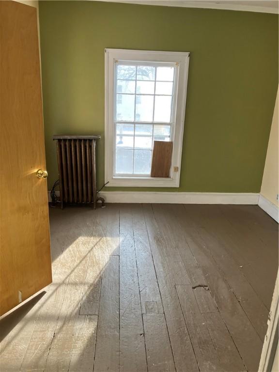 spare room featuring radiator and hardwood / wood-style flooring