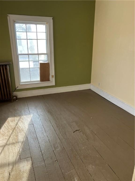 spare room with radiator heating unit and wood-type flooring