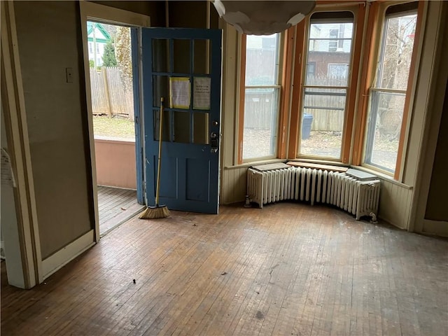 unfurnished dining area featuring hardwood / wood-style flooring and radiator heating unit