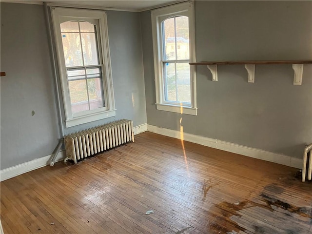 unfurnished room featuring radiator and hardwood / wood-style floors