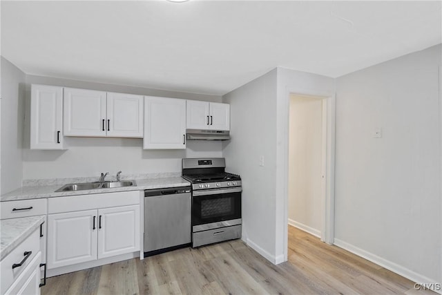 kitchen featuring sink, white cabinets, stainless steel appliances, light stone countertops, and light wood-type flooring