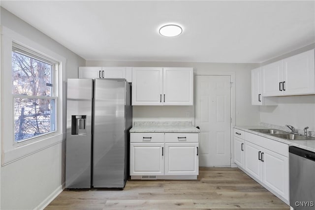 kitchen featuring stainless steel appliances, white cabinetry, and sink