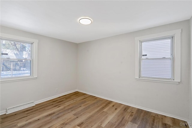 unfurnished room with baseboard heating and light hardwood / wood-style flooring