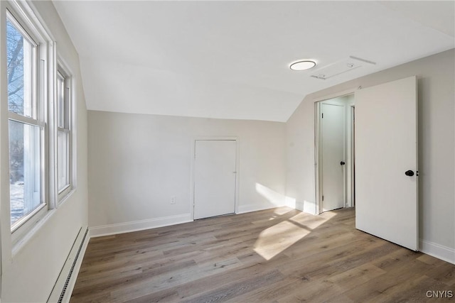 additional living space with lofted ceiling, plenty of natural light, light hardwood / wood-style floors, and baseboard heating